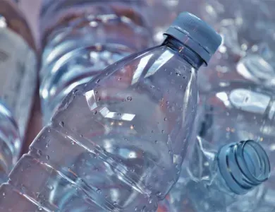 Przezroczysta plastikowa butelka z niebieską zakrętką pokryta kroplami wody.